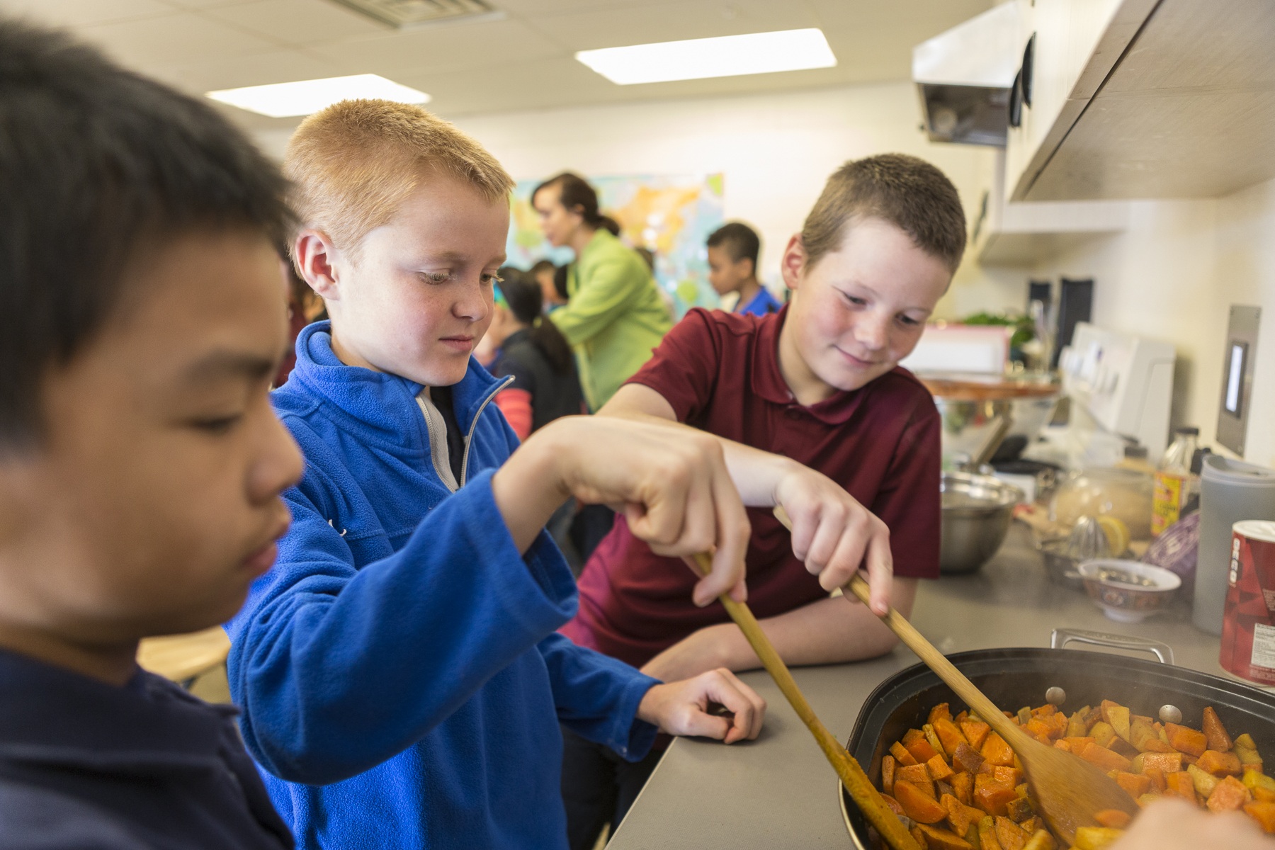 Children learning cooking skills during camp workshop
